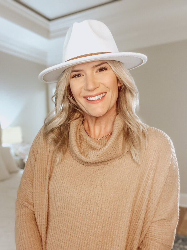 tan sweater and white hat